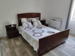 Schlafzimmer mit einem großen Bett mit einem Kopfteil aus Holz in der Unterkunft Bienvenue en sud gironde in Villandraut