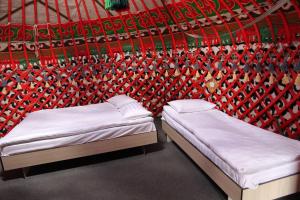 2 camas en una habitación con una pared roja en Royal Gate at Skazka Canyon, en Tong