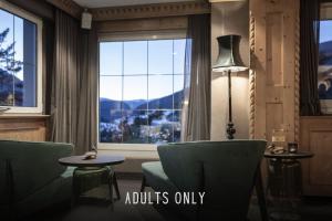 una camera con finestra, sedie e lampada di Chalet Hotel Hartmann - Adults Only a Ortisei