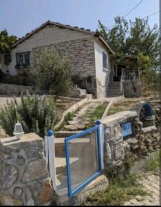 a stone house with a blue gate in front of it at Traditional Stone Cottage in Özdere