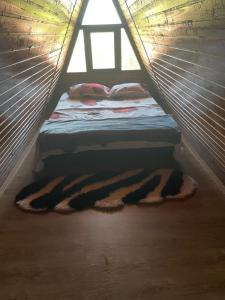 Ce lit se trouve dans une petite chambre dotée d'une fenêtre. dans l'établissement CABANĀ TIP A LÎNGĀ CASTEl, à Hunedoara