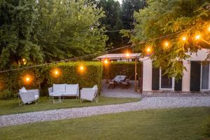 un patio trasero por la noche con sillas y luces en CASENUOVE II - Casale con parco e piscina en Castiglioncello