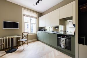a kitchen with white cabinets and a table and a chair at The Notting Hill Apartments By Hok Living - Nh3 in London
