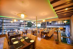 een restaurant met houten tafels en stoelen in een kamer bij Divine Kathmandu Hotel in Kathmandu