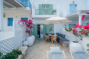 un patio con mesa, sillas y sombrilla en Villa Glaros, en Platis Yialos Sifnos