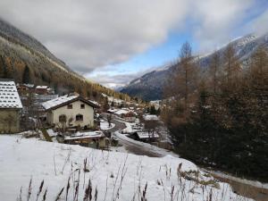 a village in the snow with a river and buildings at Gîte La Loriaz in Vallorcine