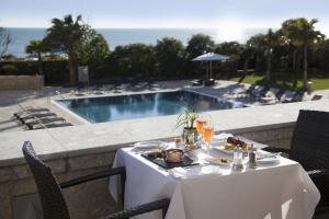 a table with food and drinks on a balcony with a pool at Grande Real Villa Itália Hotel & Spa in Cascais