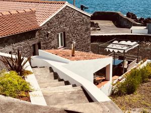 ein Steinhaus mit einer Treppe neben dem Wasser in der Unterkunft Casa da Guarda in São João + 11 Fotos