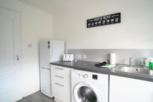 a kitchen with a washing machine and a sink at Dunalastair Apartment in Glasgow