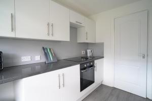 a kitchen with white cabinets and a black counter top at Dunalastair Apartment in Glasgow