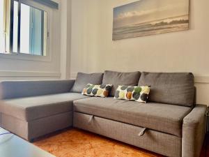 a gray couch in a living room with a window at Apartamento Allegra in Arinaga