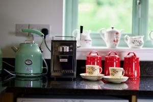Tring Grange Cottage في Wigginton: طاولة مطبخ مع آلة صنع القهوة وأكواب الشاي