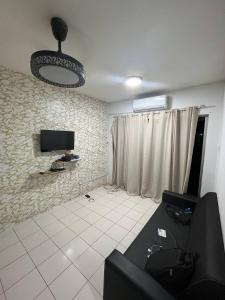 een woonkamer met een bank en een tv aan de muur bij AB HOMESTAY PUTERI BAHANG APARTMENT in Kota Kinabalu