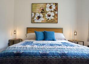 1 cama con almohadas azules y una pintura en la pared en Tring Grange Cottage en Wigginton