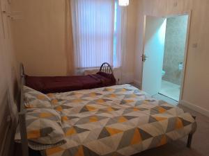 a bedroom with a bed with a quilt on it at Falcon Villa in Grimsby