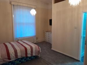 1 dormitorio con cama, ventana y vestidor en Falcon Villa en Grimsby