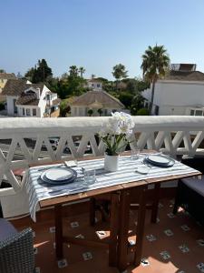 a table with plates and a vase of flowers on a balcony at Mi Sitio in Sitio de Calahonda