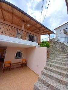 une maison avec des escaliers et un balcon avec des chaises orange dans l'établissement GKOROS HOUSE OLD TOWN, à Himarë