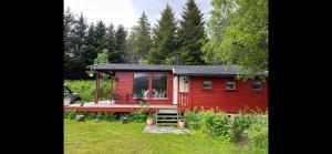 uma pequena casa vermelha com um deque num quintal em Waterfront mountain view cabin Lofoten em Liland