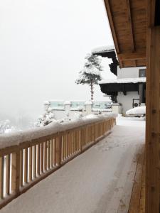 uma cerca coberta de neve ao lado de uma casa em Soul Mountain Lodge em Mühlbach am Hochkönig