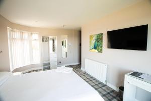 um quarto com uma cama branca e uma televisão de ecrã plano em Poseidon Inn em Lossiemouth