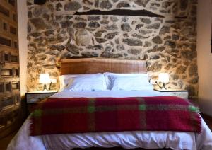 1 dormitorio con 1 cama y pared de piedra en La Casa del Guarda - Turismo Sotosalbos, en Sotosalbos