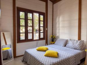 a bedroom with a bed with yellow pillows on it at Cantareira - Deck House in Mairiporã +42 photos