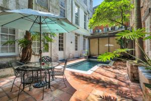 a patio with a table and an umbrella and a pool at Hotel de L'eau Vive in New Orleans