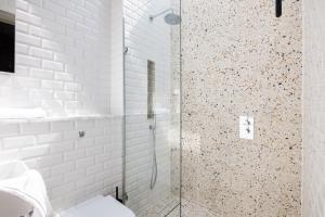 W łazience wyłożonej białymi kafelkami znajduje się przeszklony prysznic. w obiekcie The Notting Hill Apartments By Hok Living - Nh4 w Londynie