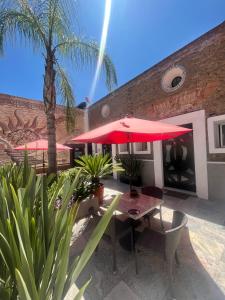 une terrasse avec des parasols rouges, une table et des chaises dans l'établissement SOLSTICIO 212, à Cholula