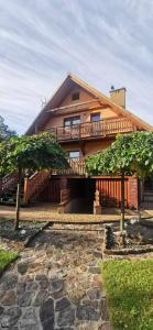 a large wooden house with a balcony and two trees at Zielkowa Ostoja in Niesiołowice