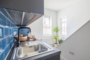a kitchen with a sink and a blue tiled wall at Radcliffe Studios in Wolverton