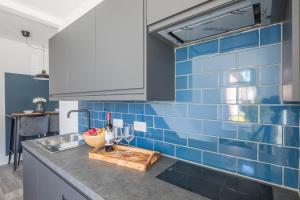 a kitchen with blue tiles on the wall and a sink at Radcliffe Studios in Wolverton