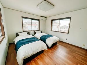 two beds in a room with two windows at シテコベハウス in Yokosuka