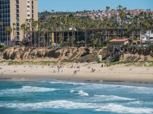 a group of people on a beach near the ocean at Pacific Terrace Hotel in San Diego