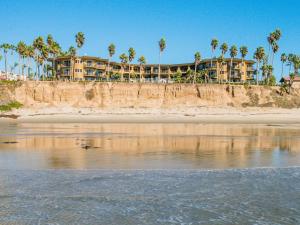 a building on the beach with palm trees and the water at Pacific Terrace Hotel in San Diego