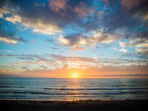 a sunset on the beach with the ocean at Pacific Terrace Hotel in San Diego