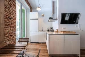 une cuisine avec des placards blancs et un mur en briques dans l'établissement Apartamento centrico y comodo Preciados, à Madrid