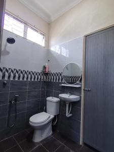 y baño con aseo, lavabo y espejo. en FIYA ViLA HOMESTAY, en Ketereh