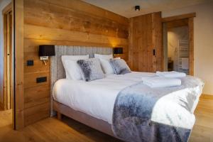 Schlafzimmer mit einem großen Bett und Holzwänden in der Unterkunft Chalet Happyview - OVO Network in Le Grand-Bornand