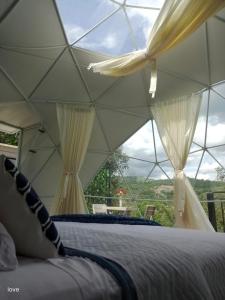 een slaapkamer met een bed met gordijnen en een raam bij Glamping romantico en Vista Hermosa disfruta de la naturaleza en un ambiente privado y acogedor in La Mesa