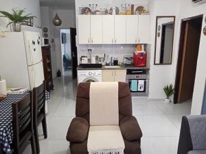 a kitchen with white cabinets and a chair in a room at Yafe Nof 35 in Ashqelon