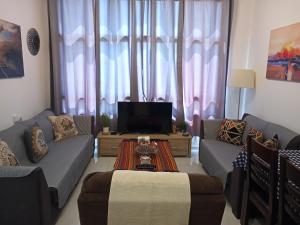 a living room with two couches and a tv at Marina Breeze in Ashqelon