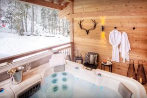 a jacuzzi tub in a room with a window at Chalet Riparian - OVO Network in La Clusaz