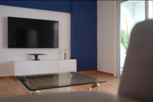 a living room with a tv and a glass table at Gezellige villa met prachtig zicht en zwembad in Arona