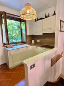 eine Küche mit weißen Schränken, einem Fenster und einem Kronleuchter in der Unterkunft CASA VACANZE CERNIZZA in Duino