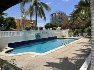 a swimming pool with a white fence and palm trees at Finest Accommodation Renfrew Place 1 Bedroom Apt # 42 New Kgn 4--12 Renfrew Rd in Kingston