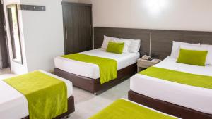 a hotel room with two beds with green sheets at Hotel San Juan Internacional in Bucaramanga