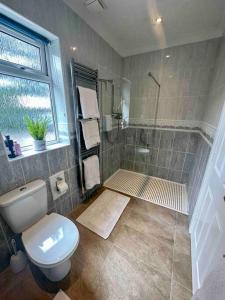 a bathroom with a shower and a toilet and a window at Spindrift, Spacious bungalow near beach in Hamworthy