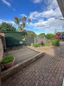 a backyard with a wooden deck with a green building at Spindrift, Spacious bungalow near beach in Hamworthy